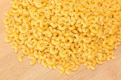 a-heap-of-uncooked-chifferi-rigati-pasta-on-wooden-kitchen-board-fat-and-unhealthy-food-classic-dry-macaroni-italian-culture-and-cuisine-raw-pasta-photo
